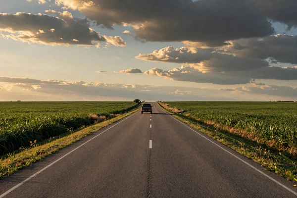 A pickup truck on a long country road through Midwest farmland - long distance rural dating
