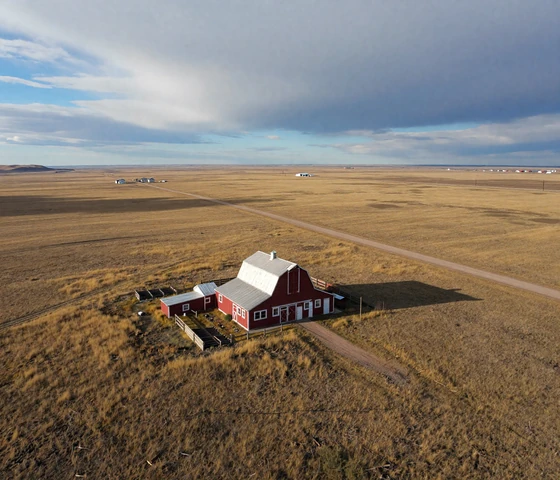 Isolated Montana ranch homestead surrounded by endless prairie grassland showing rural dating distance challenges