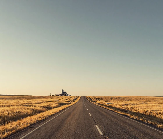 Long straight highway through Kansas prairie wheat fields showing vast distances between rural communities for farm dating