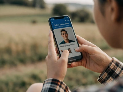 Woman checking a verified dating profile on her phone in a rural setting - dating site safety tips